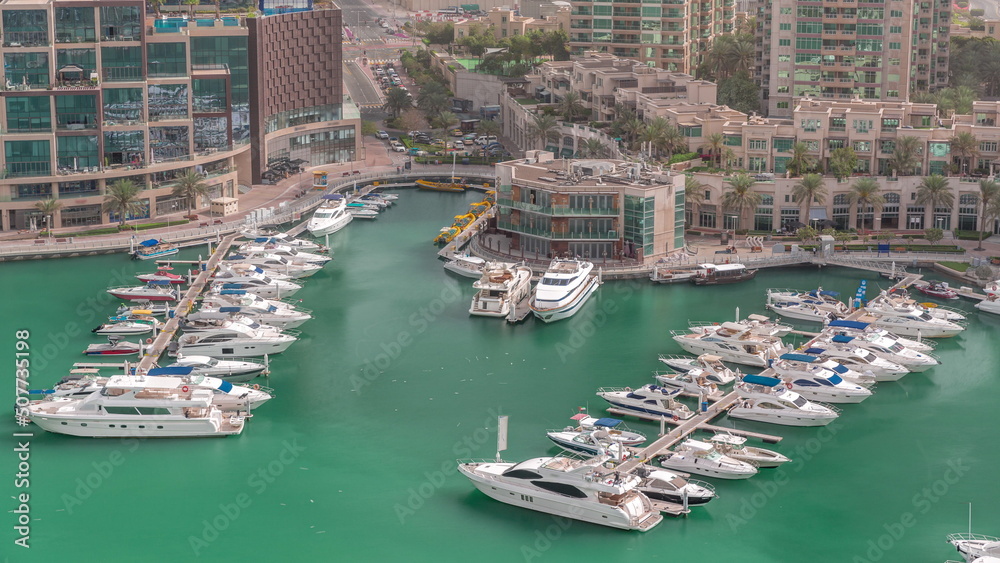 Luxury boats and yachts docked in Dubai Marina aerial timelapse.