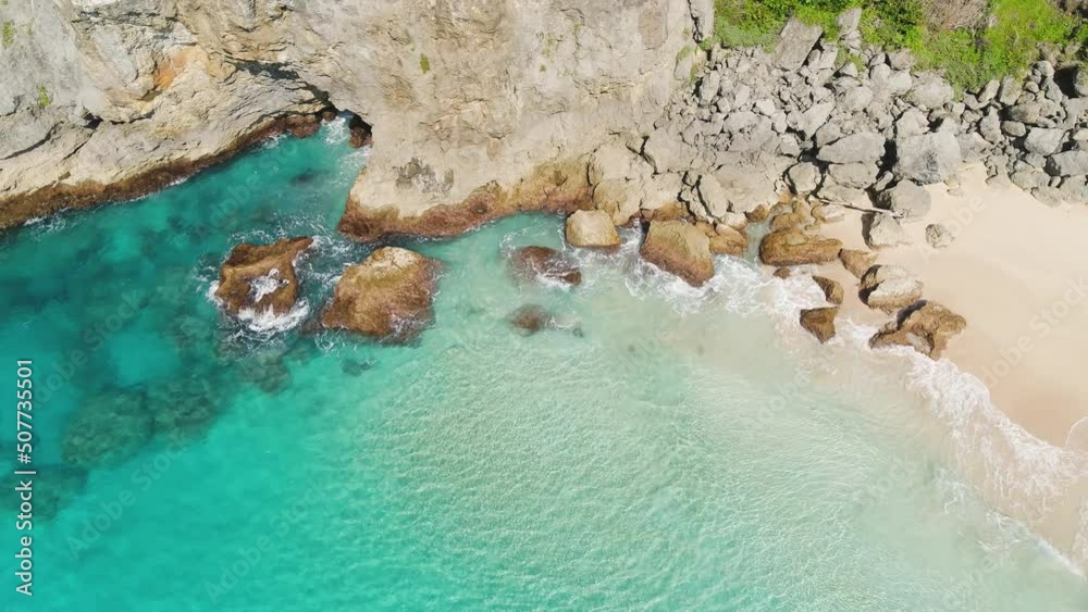 Sunny sea coast of Cuba with rocks and sandy beach. Sea wave on white sand. Rocky sea coast. Beautiful seascape. Turquoise sea with sun glare. Blue lagoon on a sunny day.