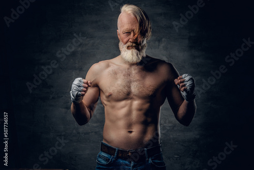 Photo of topless senior boxer with stylish hairstyle and muscular build against dark background. © Fxquadro