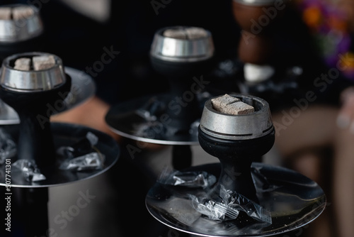 Smoldering embers in kaloud on hookah. Hookah smoking concept. Kalaud, charcoal tongs on hookah plate stands in nature.