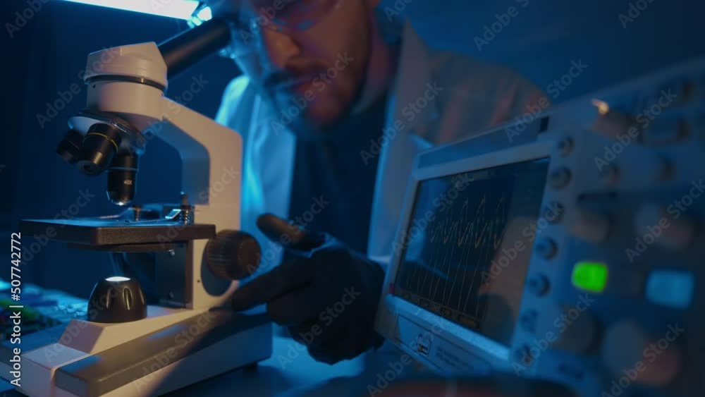 A man scientist is looking into microscope, biochemical research. Scientific and medical lab instrument. A doctor is search for vaccine to treat diseases in laboratory for medicine study A man scientist is looking into microscope, biochemical research. Scientific and medical lab instrument. A doctor is search for vaccine to treat diseases in laboratory for medicine study