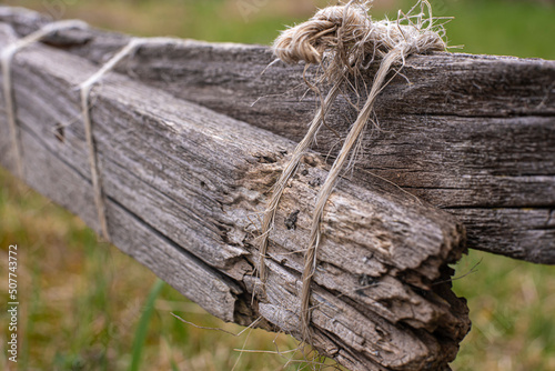 a broken wooden fence repaired with a cord