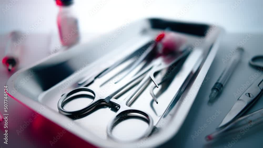Medical instruments in steel tray on table for surgery. Preparing of surgical tools for a operation. Scalpels and forceps and tweezers. Surgery or emergency case and ambulance or treatment concept.