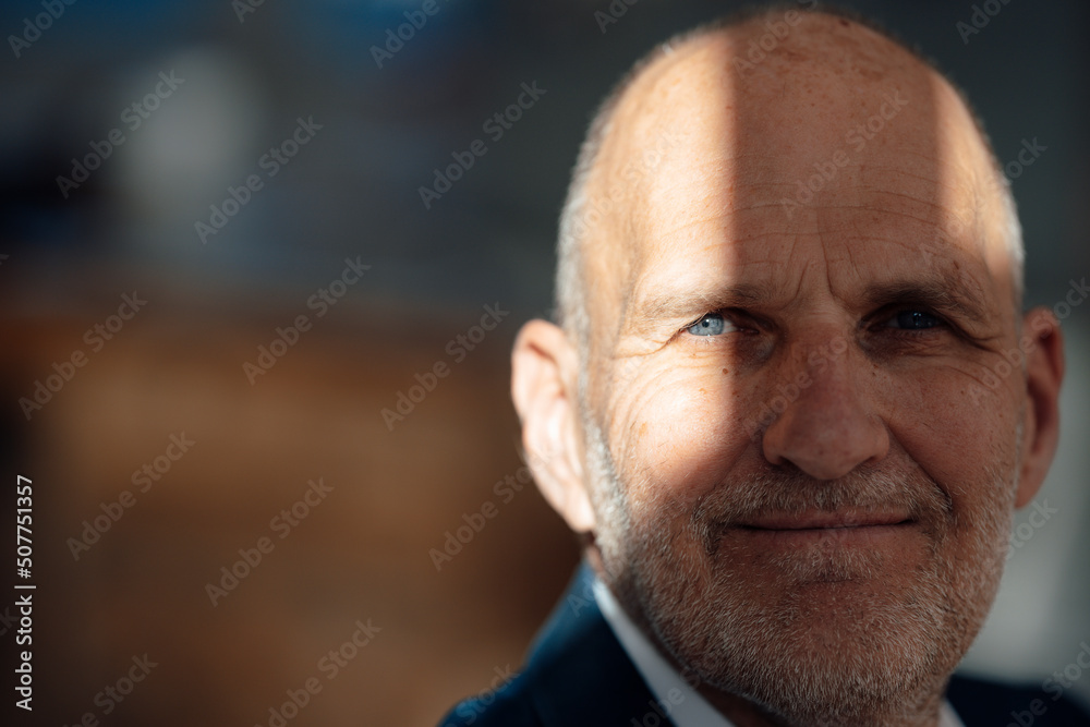 Smiling senior businessman with sunlight on face in office Smiling senior businessman with sunlight on face in office