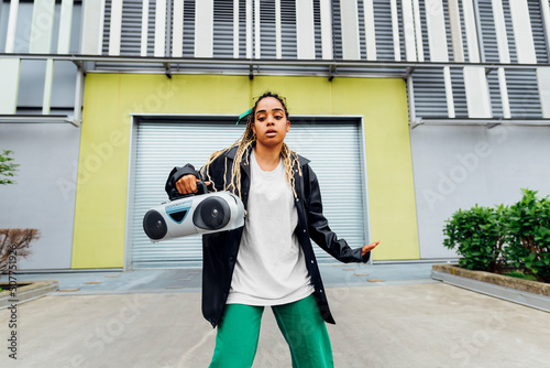 Young woman with boom box dancing in front of shutter photo