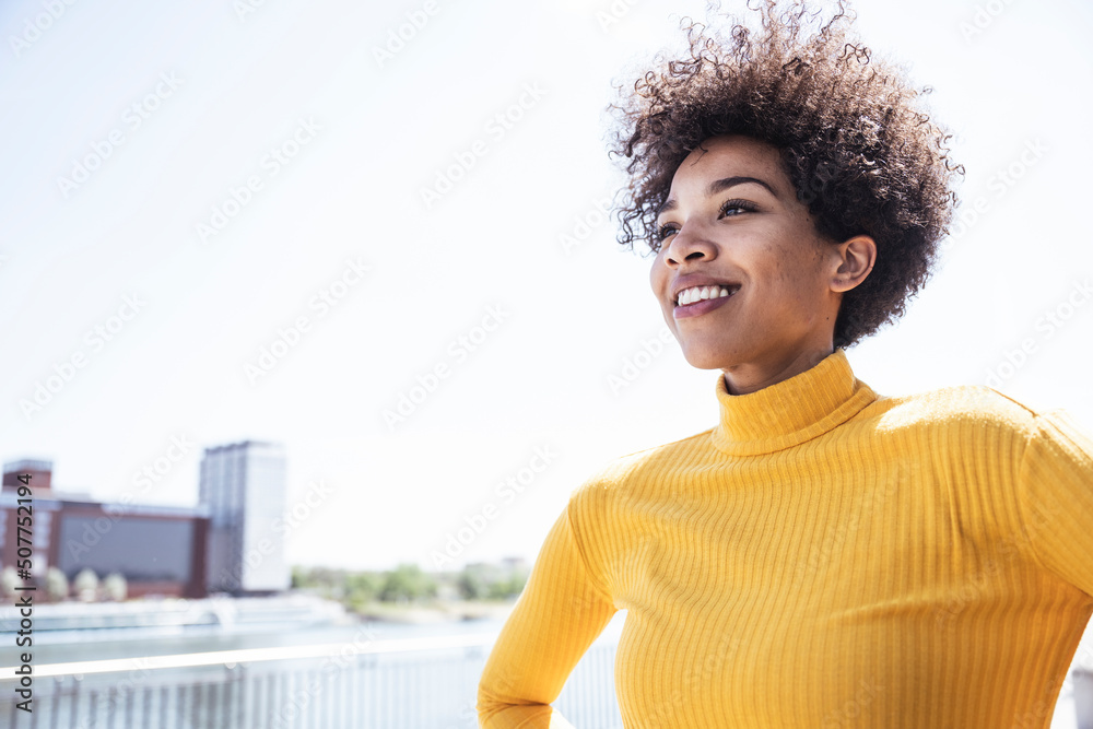 Smiling woman with Afro hairstyle on sunny day