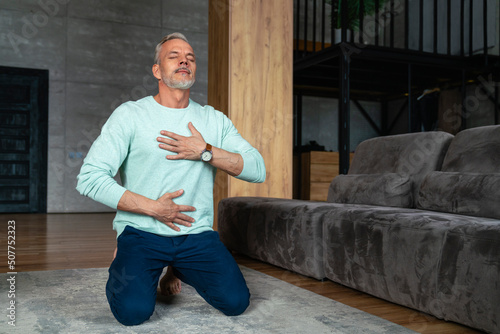 Man with eyes closed doing breathing exercise at home photo