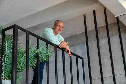 Man leaning on railing at home