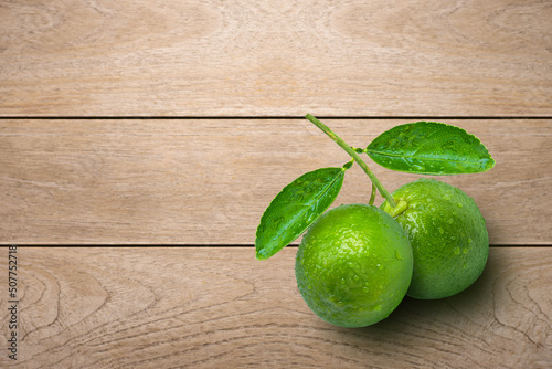 Fresh green lime with greren leaf isolated on wooden table background. Top view. Flat lay. photo