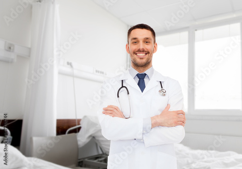 medicine  profession and healthcare concept - smiling male doctor with stethoscope over hospital ward background
