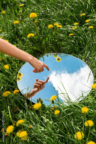 Fototapeta Naklejka Na Ścianę i Meble -  nature concept - hand touching sky reflection in round mirror on summer field