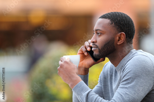 Man with black skin talking on phone drinking in a coffee shop