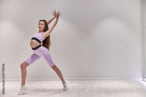 Young beautiful girl stretches before dance class and look at the camera