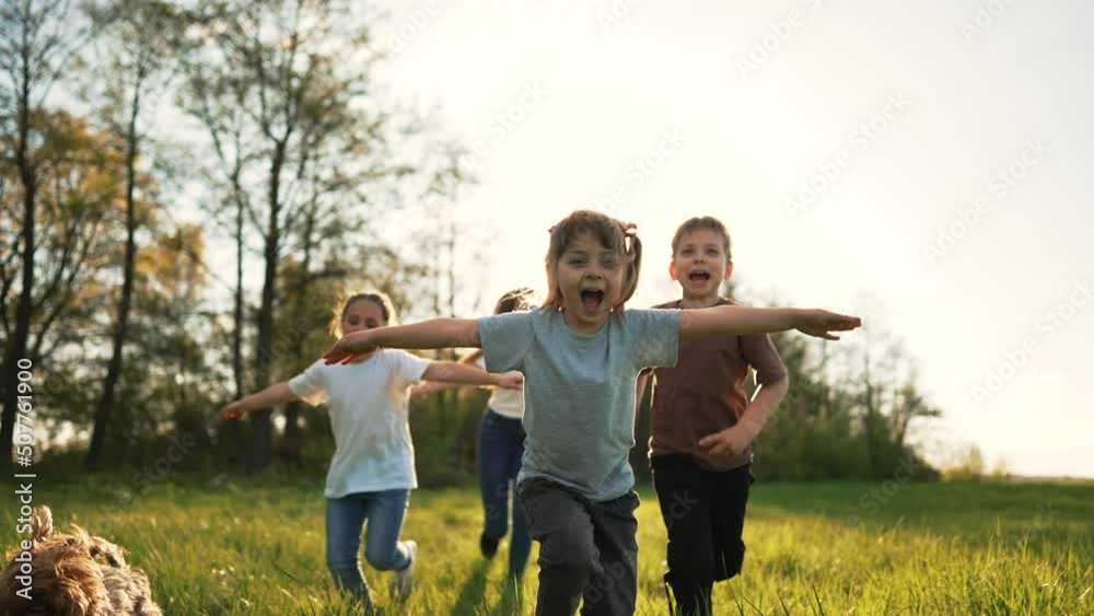 Children play in spring vacation park.Active happy group of kid run with a dog on grass in field in summer.Family in nature with pet.Child on play.Happy family concept.School in garden with dog