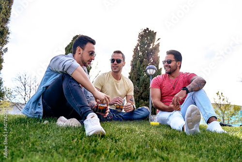 Group of friends drinking refreshing drinks while relaxing together outdoors in the park. Friendship concept.