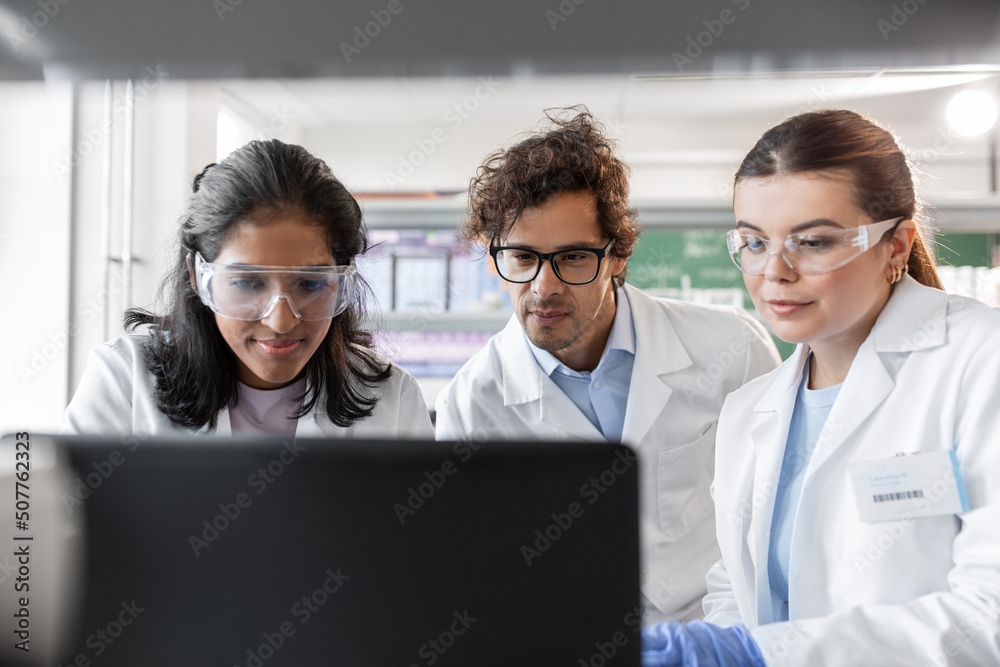 science research, work and people concept - international team of scientists with laptop computer working in laboratory science research, work and people concept - international team of scientists with laptop computer working in laboratory