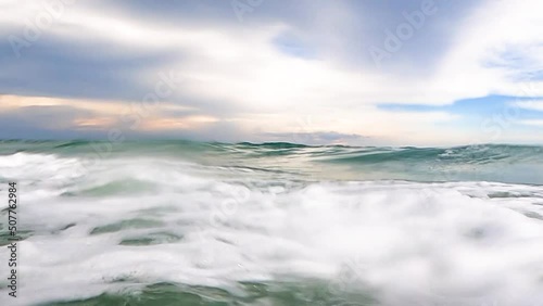 Point of view a big and power wave sea attack towards the surface until foaming and splash to camera like point of view between sky and underwater 