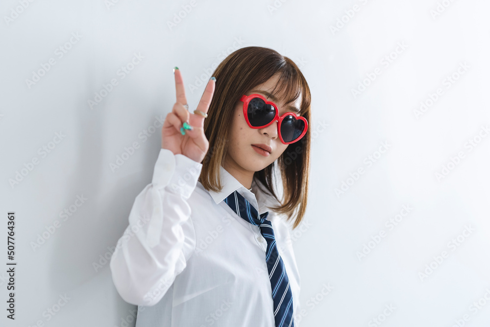 ハートのサングラスをかけてピースサインをする女子高生 ハートのサングラスをかけてピースサインをする女子高生