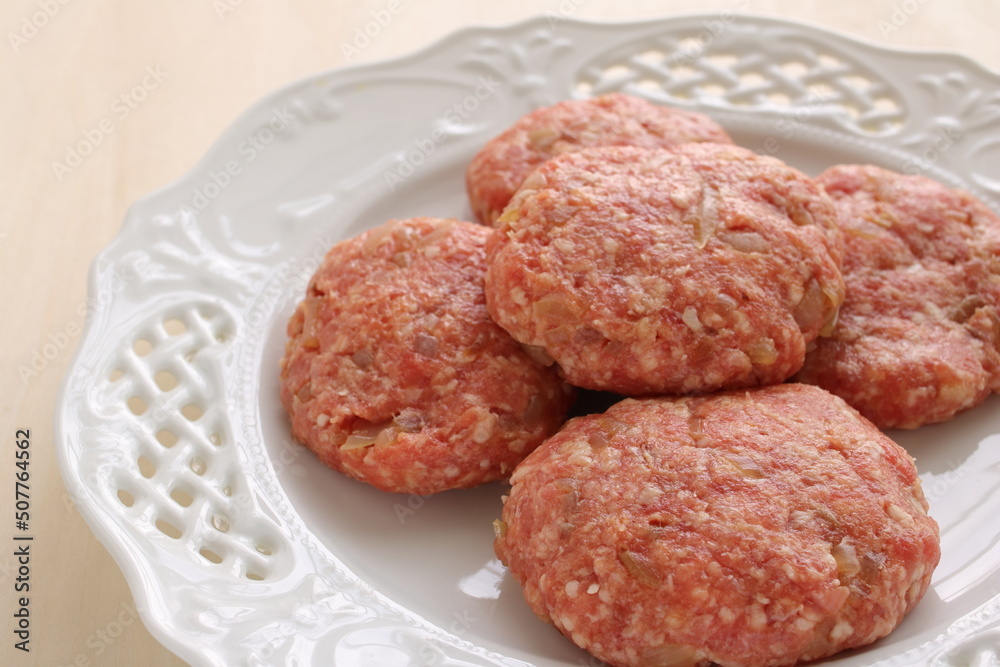 Homemade hamburger patty on white plate for prepared cooking ingredient Homemade hamburger patty on white plate for prepared cooking ingredient