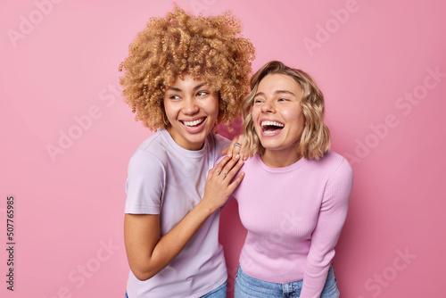 Принти на полотні Joyful happy young women laughs out gladfully dressed in casual clothes notice something funny giggle positively express positive emotions isolated over pink background