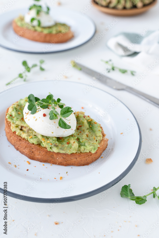 Beautiful breakfast with avocado and poached egg. Pea microgreens. Gray background with breakfast