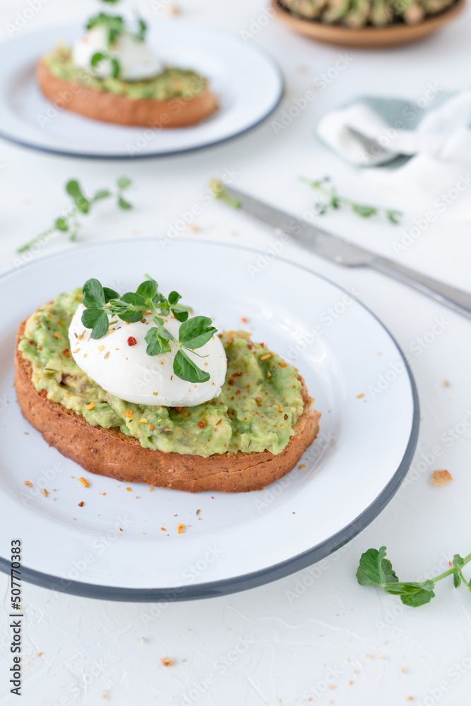 Beautiful breakfast with avocado and poached egg. Pea microgreens. Gray background with breakfast Beautiful breakfast with avocado and poached egg. Pea microgreens. Gray background with breakfast