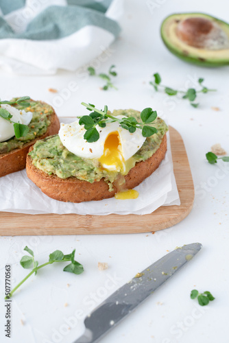Beautiful breakfast with avocado and poached egg. Pea microgreens. Gray background with breakfast