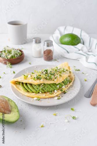 Nice breakfast with avocado. Omelet with microgreens. Gray background with breakfast