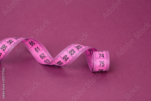 Colorful tape measure spiral with copyspace pink background