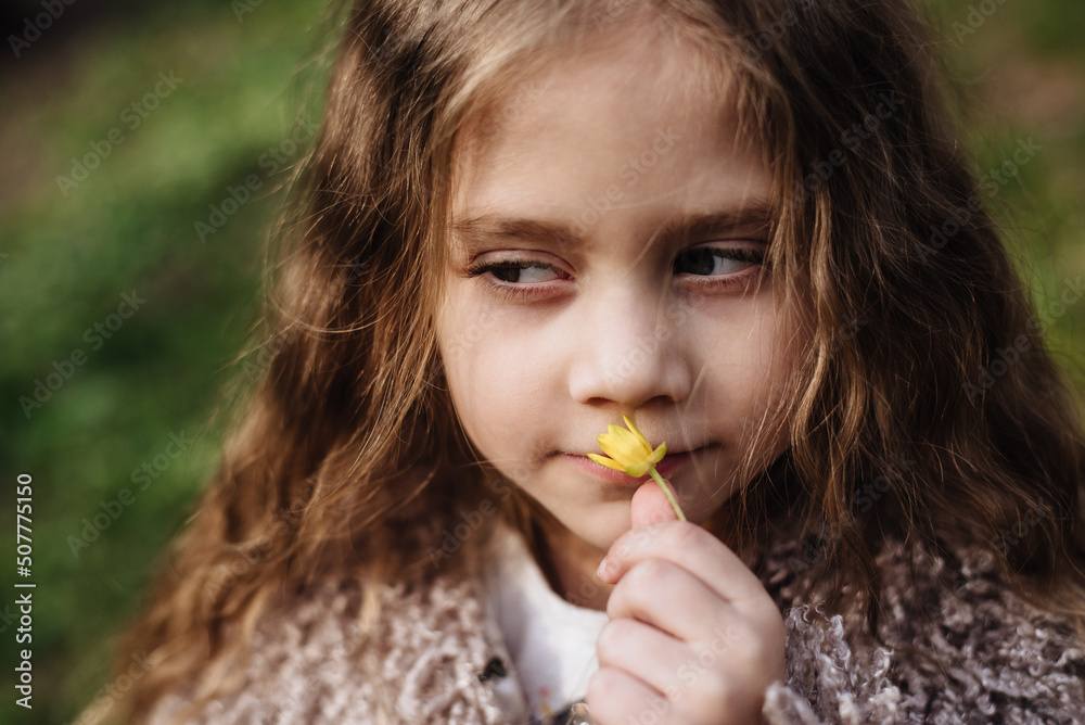 Cute baby enjoys the smell of a yellow plucked flower. Portrait of a beautiful girl holding flowers Cute baby enjoys the smell of a yellow plucked flower. Portrait of a beautiful girl holding flowers