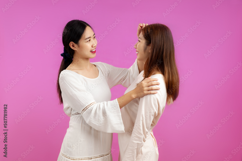 Asian women lgbt couple lesbian in white dress isolated on pink color background. Pride month concept.