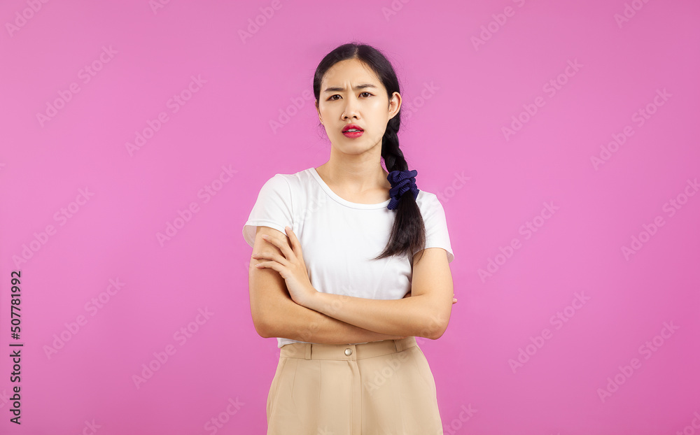 Asian woman in white shirt posing arms crossed and feeling upset on the pink screen background. Asian woman in white shirt posing arms crossed and feeling upset on the pink screen background.