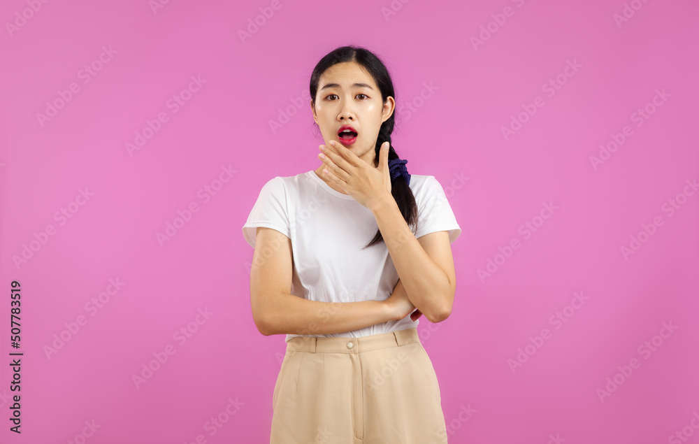 Young asian woman in white t-shirt posing surprised face and hands isolated pink color background.