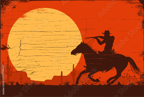 Silhouette cowboy riding a horse carrying a gun at sunset.