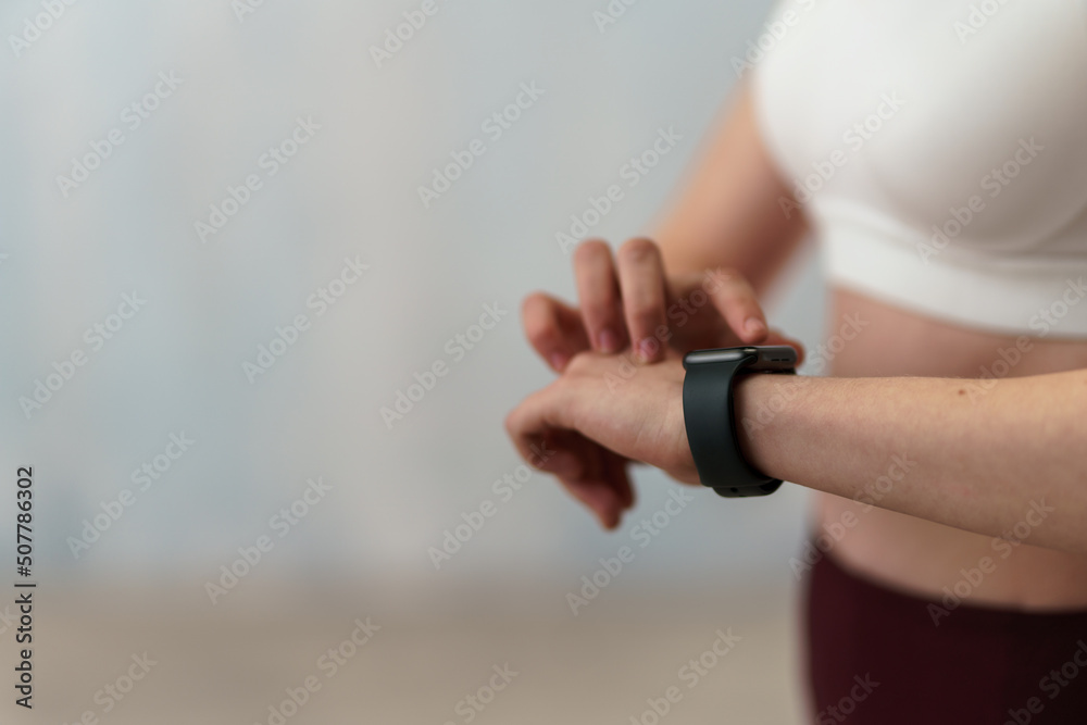 Close up shot of young woman setting and looking at sports smartwatch. Fitness female checking her performance.