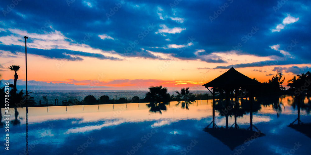 Sunset over swimming pool with palm trees, Tenerife Sunset over swimming pool with palm trees, Tenerife
