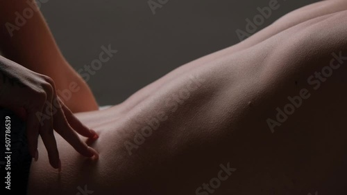 A woman runs her hand over a man's back close-up. Passion and love in the relationship of a married couple.