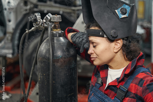 Woman auto mechanic standing near gas cylinder in garage