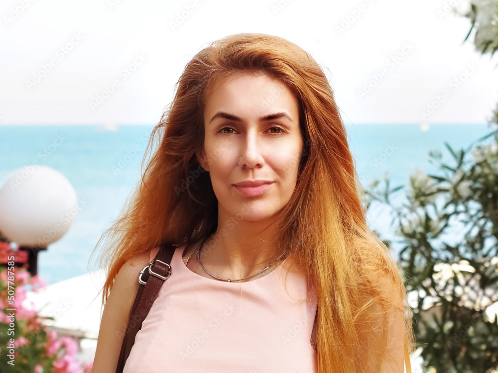 Portrait of a fair-haired woman standing on a summer day in front of the sea. Close-up photo. Summer southern holidays. Soft focus. Portrait of a fair-haired woman standing on a summer day in front of the sea. Close-up photo. Summer southern holidays. Soft focus.