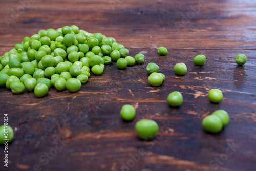 Fresh peeled green pease on a brown wooden table with copy space. Still life of green peas in pods with pea shoots on wooden table