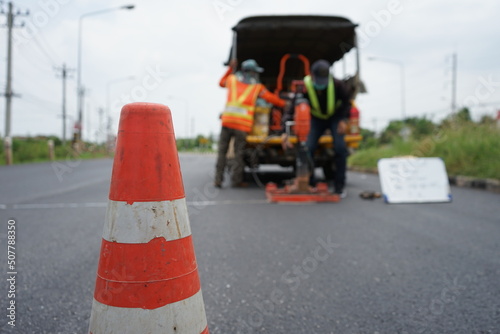 Red rubber cone and blurry background image of road maintenance agency work.
