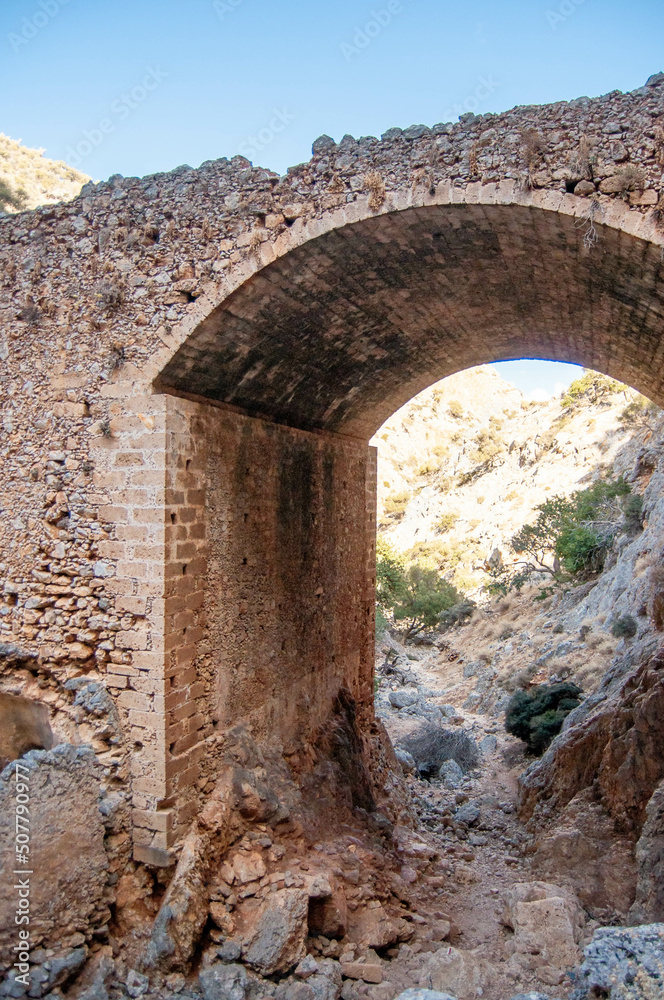 Ancient ruined stone arch in the mountains, Crete island, Greece.
