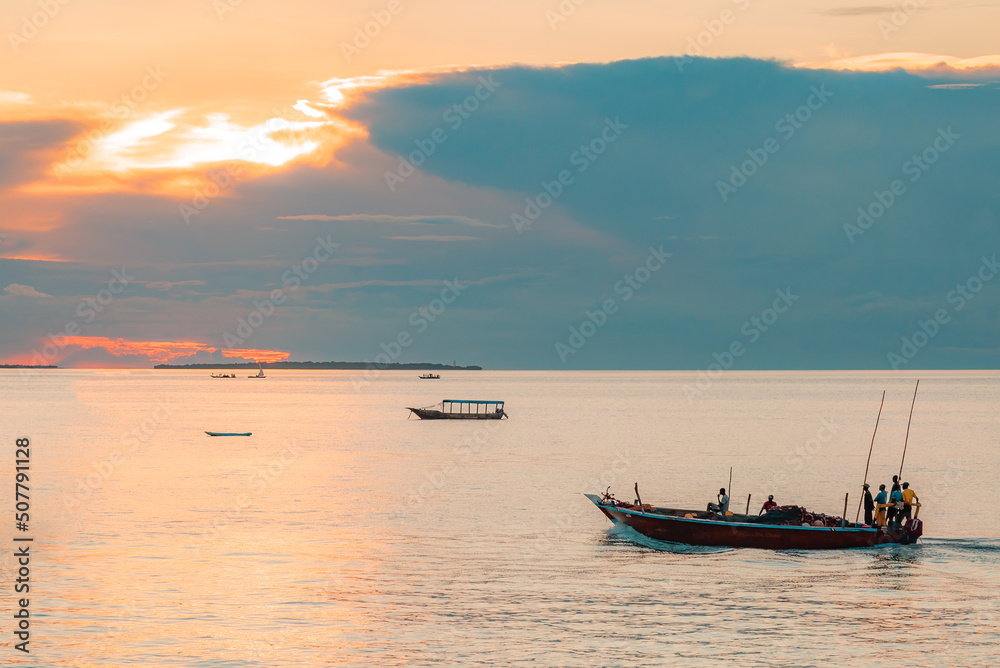 Fishing boat with fisherman return home, Indian ocean on a scenic sunset. Zanzibar, Tanzania