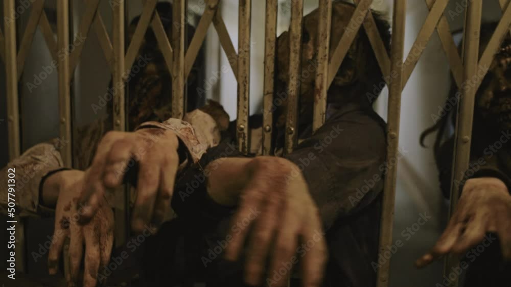 POV of three zombies trying reaching with their hands invisible victim who hiding behind old elevator gate