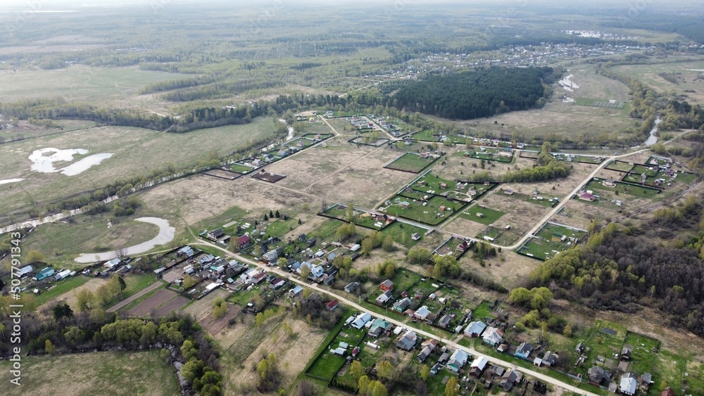 view from the height of the village with streets, plowed fields, meadows in summer. Rural landscape from a height shooting on a quadcopter, green areas