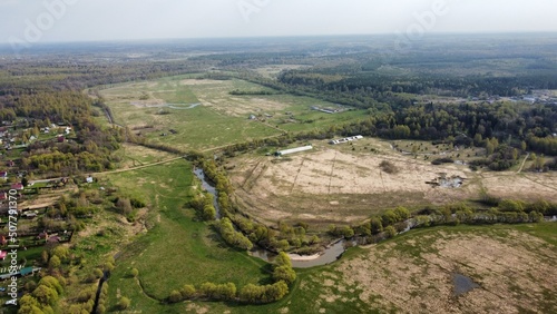 view from the height of the village with streets, plowed fields, meadows in summer. Rural landscape from a height shooting on a quadcopter, green areas