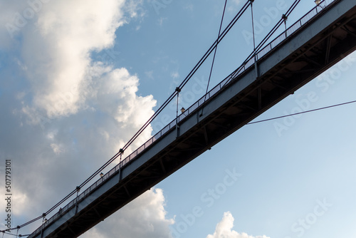 Silhouette of pedestrian bridge on background of blue sky with clouds