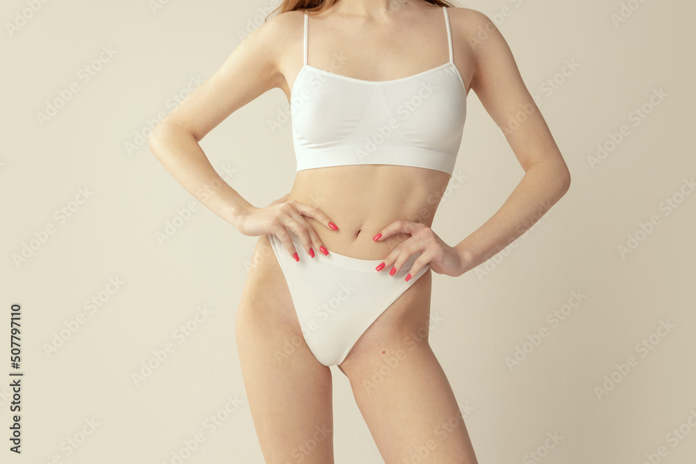 Cropped image of slim female body in white cotton underwear isolated over grey studio background