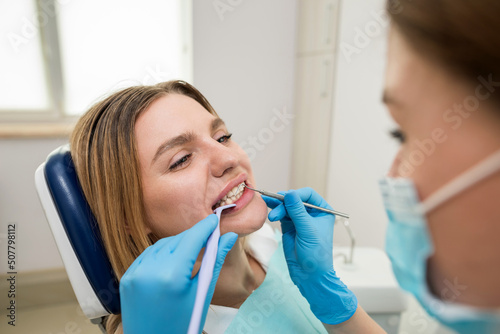 Photo of a smiling female patient being treated in a dental clinic.