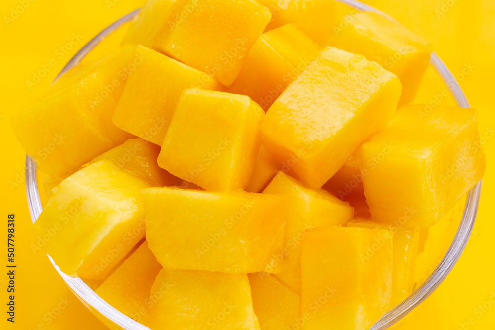 Yellow mango cube slices on yellow background.